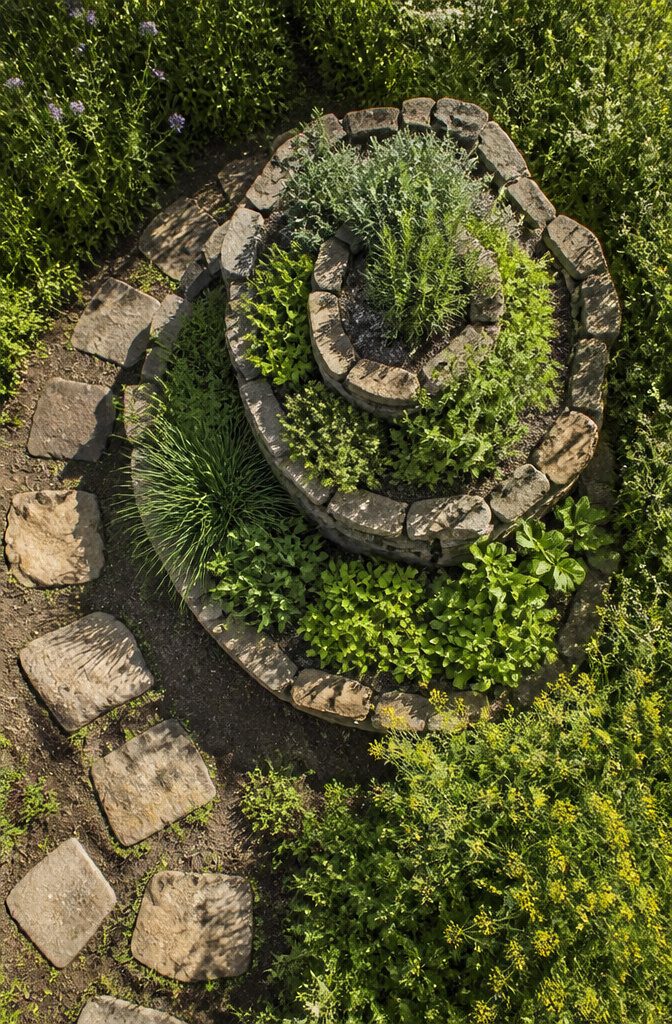 21 Herb Garden Ideas for Raised Beds, Containers & Small Spaces (2026) 13 A spiral garden structure with various herbs planted around it.
