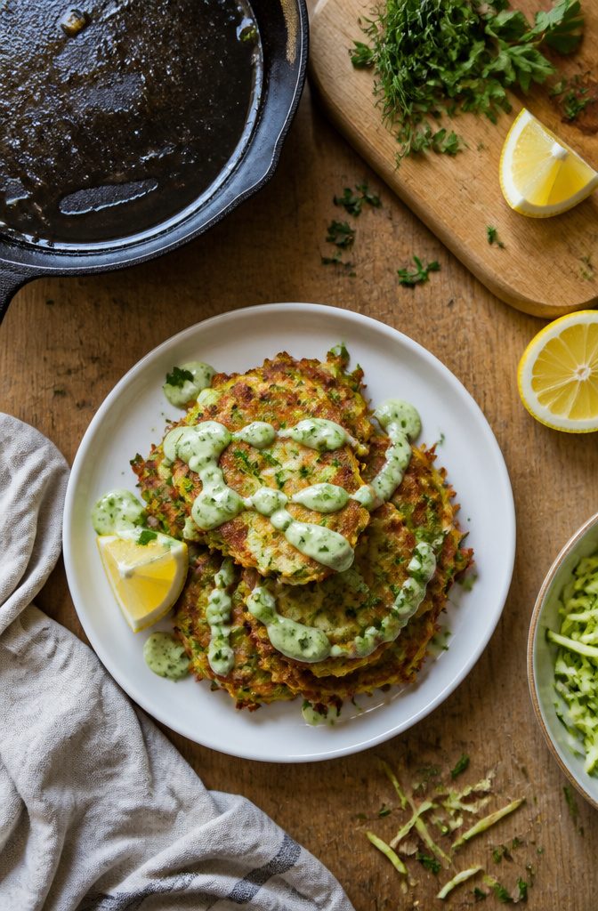 Golden-brown zucchini fritters frying in hot oil in a skillet.